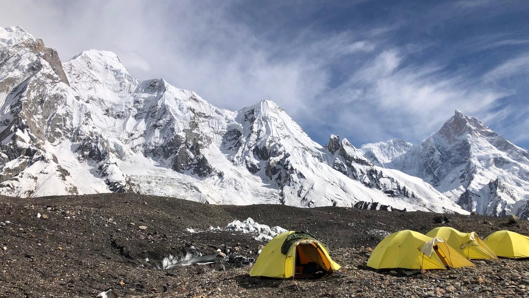 Tents pitched on the moraine below snow-covered Karakoram peaks
