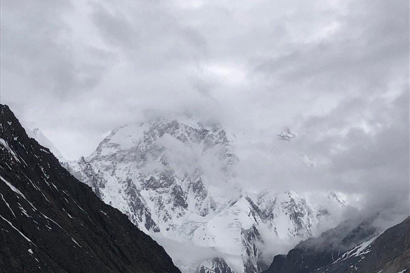 K2 rising above the glacier, its summit in cloud