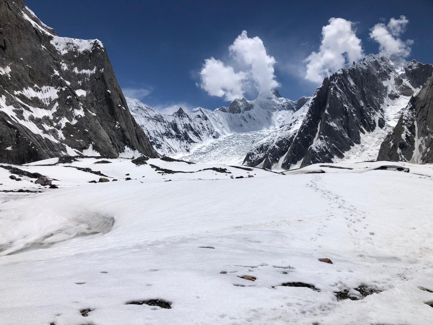 Deep snow covering the glacier with a line of footprints leading away